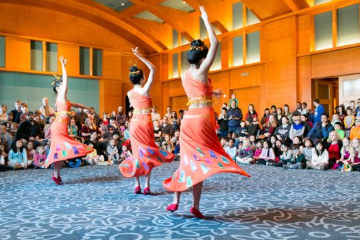 Three dancers performing while a crowd watches in Mia’s reception hall.