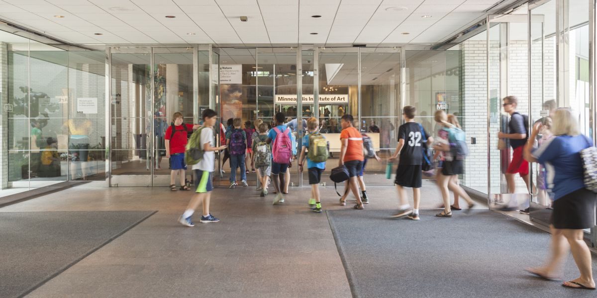 A crowd of school children walk through Mia's main entrance.