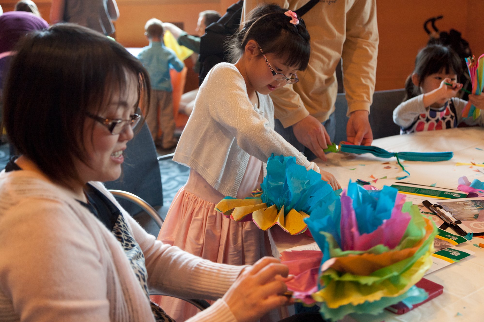 A daughter and mother making tissue paper flowers at a Mia event