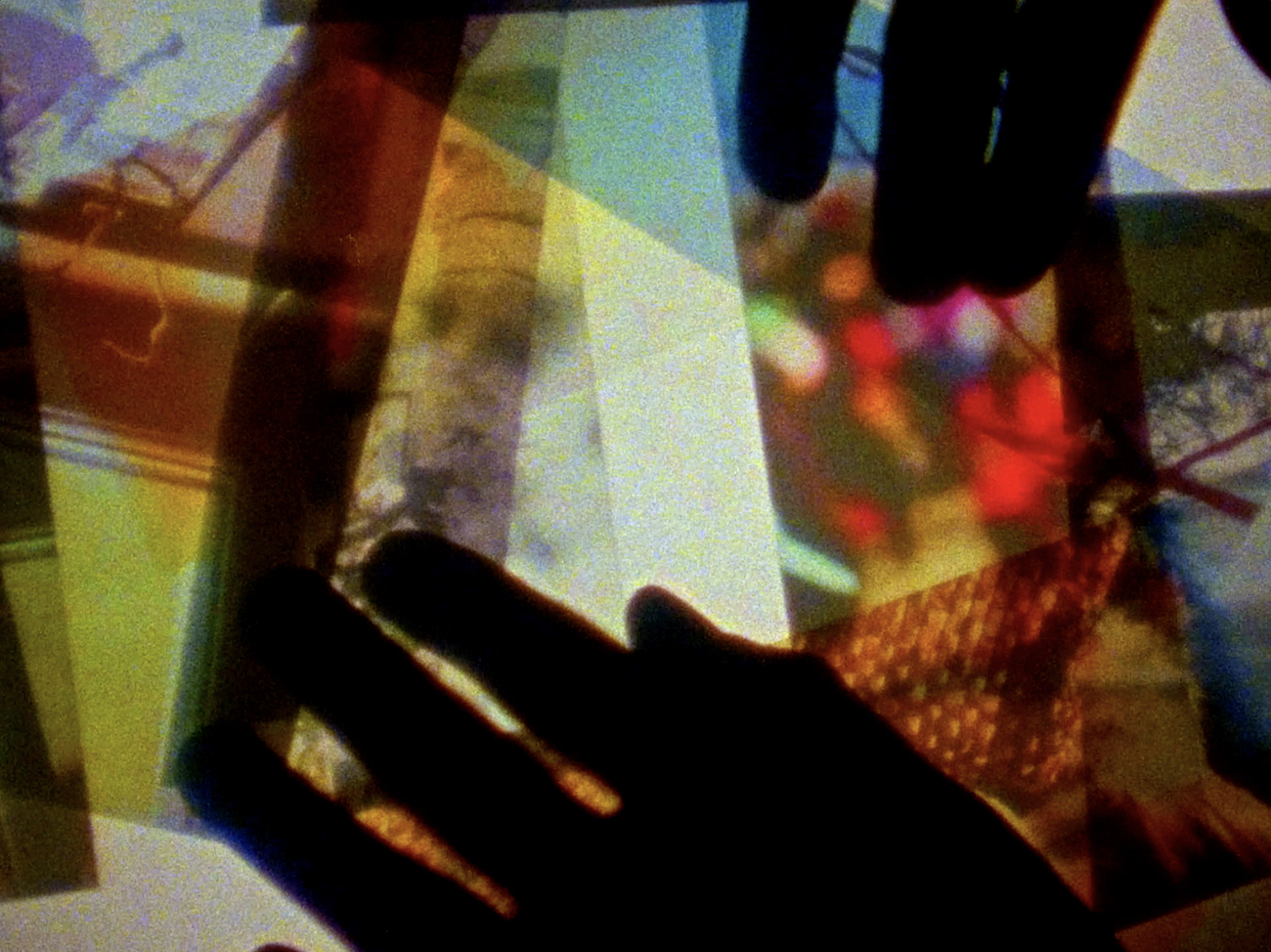 Colorful photos appear transparent against a white backlight. The silhouette of hands appears atop the photos.