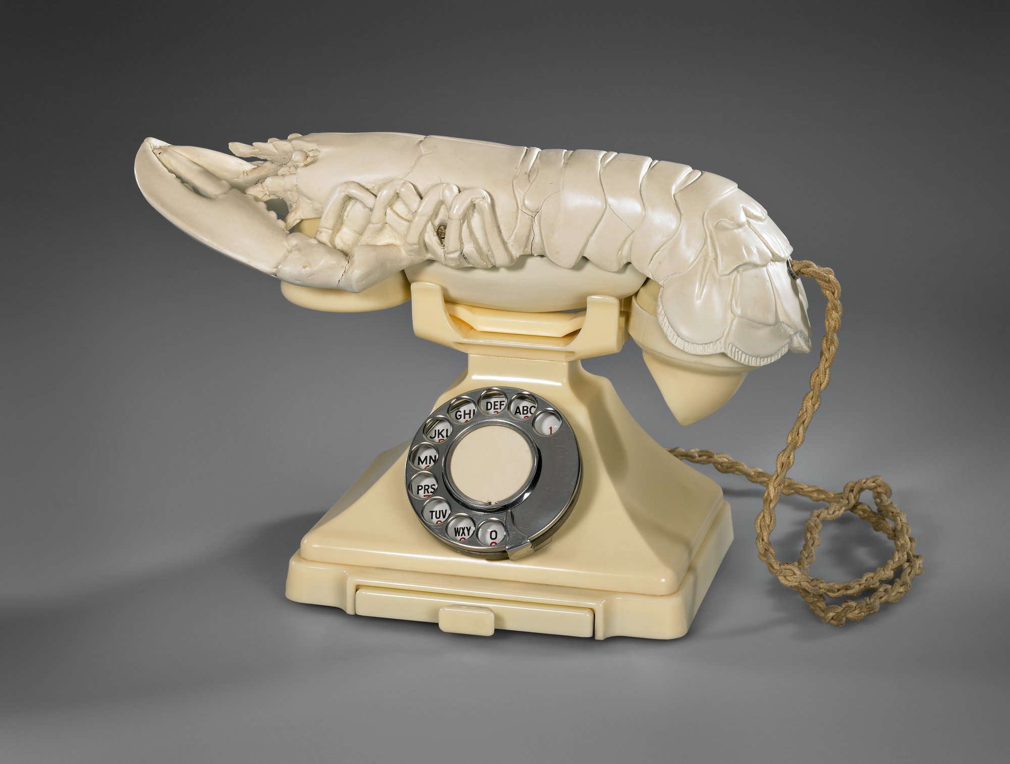 A beige toned old fashioned telephone with a tan colored lobster receiver.