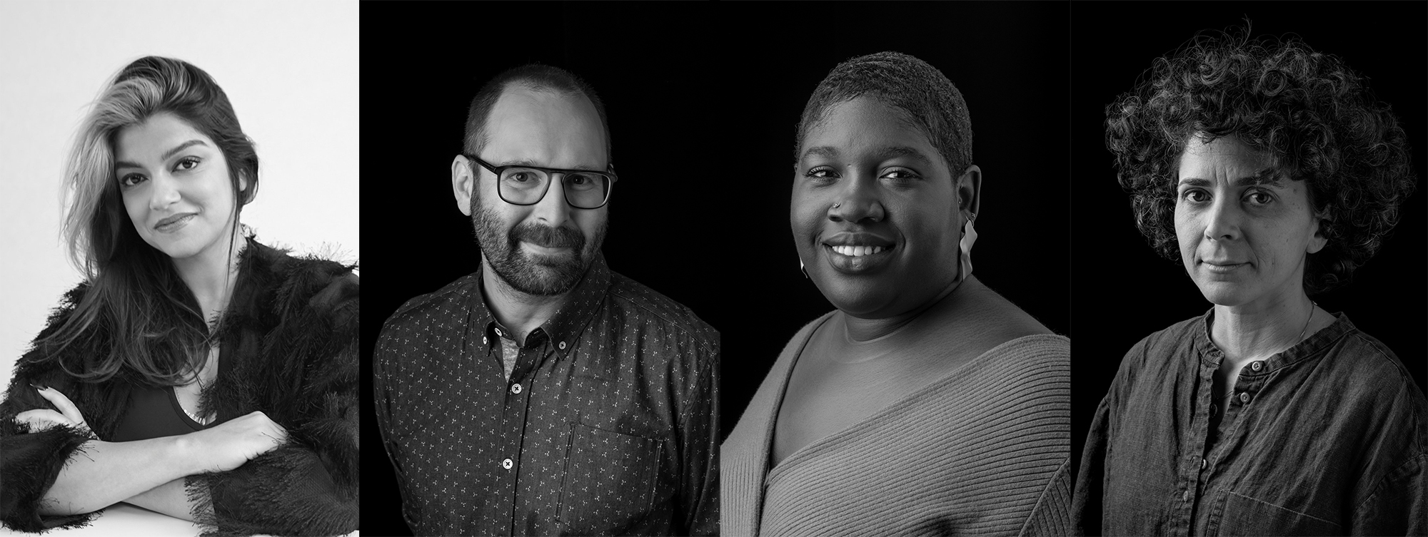 In a black and white photo, four people are smiling towards a camera.