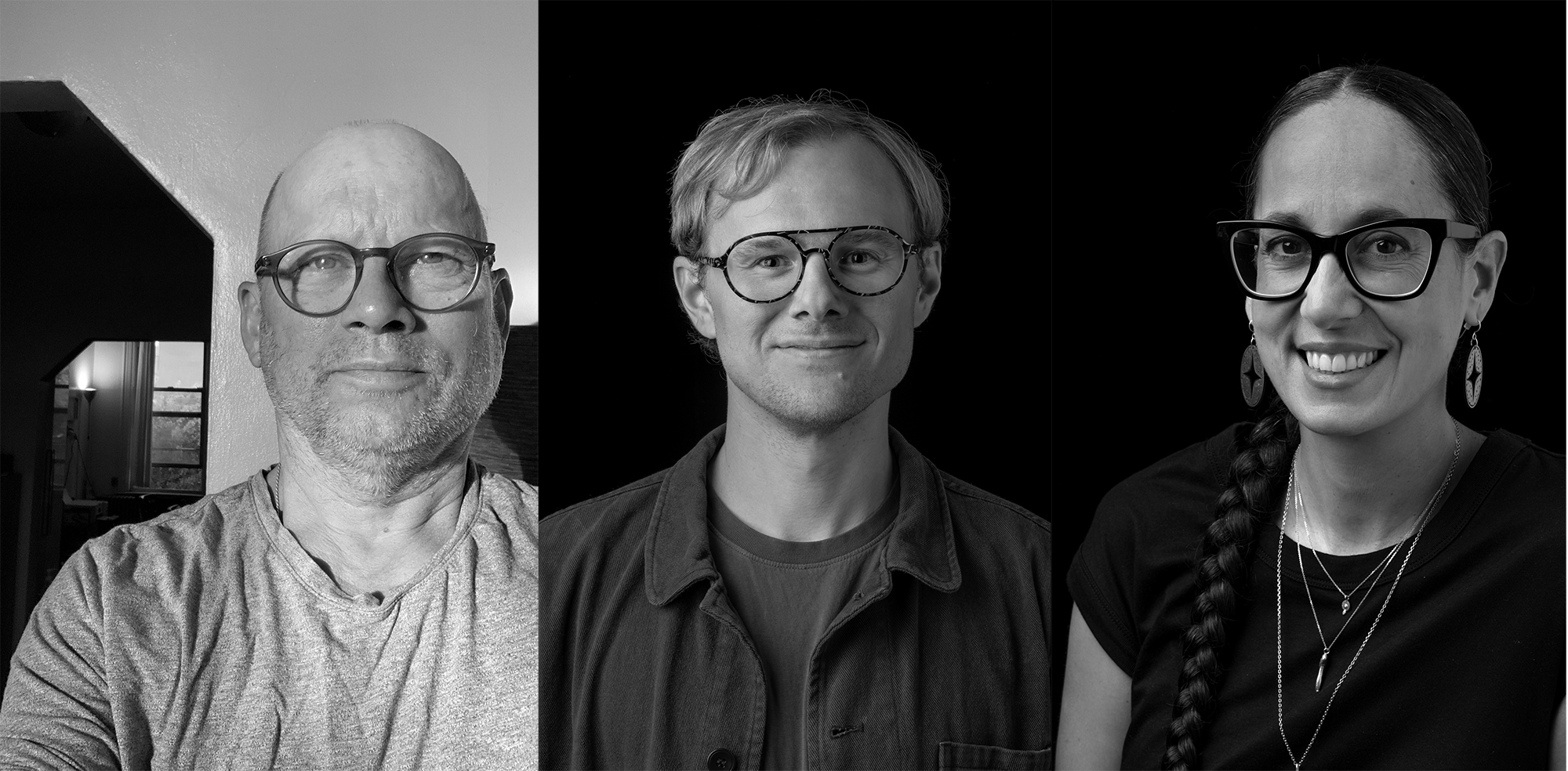 In a black and white photo, three artists are smiling towards the camera.