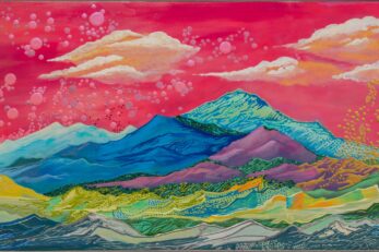 Colorful scene of mountains in blue, green, teal, purple, and orange with a bright pink sky