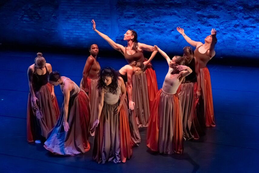 Group of dancers in graceful poses with long skirts on stage