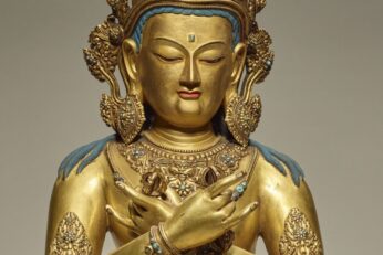 A glittering gold figure of a deity with hands crossed.