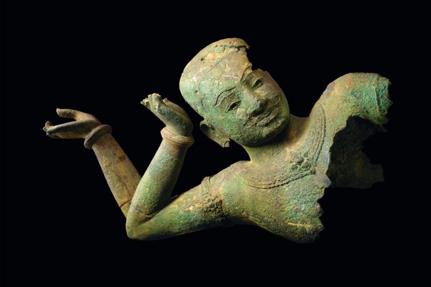 bronze sculpture of a reclining Vishnu showing his face with two arms bent at the elbow