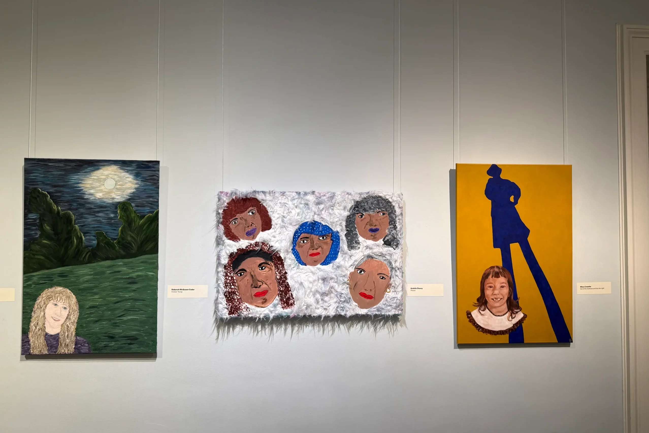 photograph of three paintings hanging on the wall
