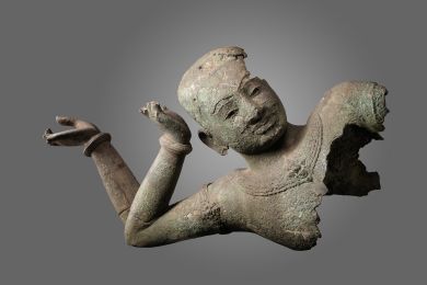 bronze sculpture of a reclining Vishnu showing his face with two arms bent at the elbow
