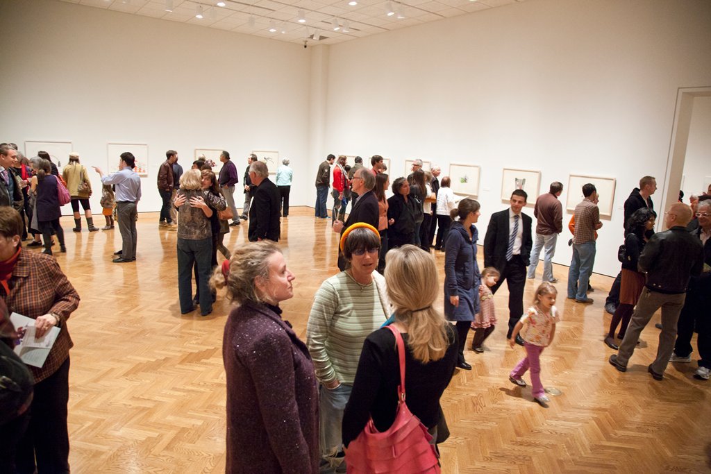 Photograph of many people standing and talking in a gallery