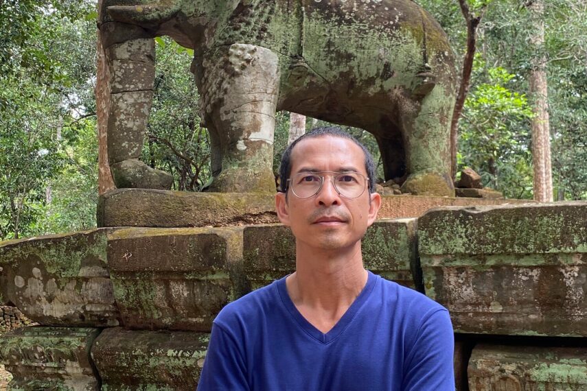 Photo of Sopheap Pich standing in front of a stone elephant sculpture at a temple in Cambodia