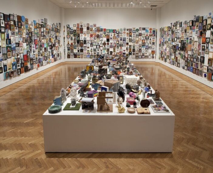 Photograph of a Mia gallery with walls and giant pedestal covered with small artworks