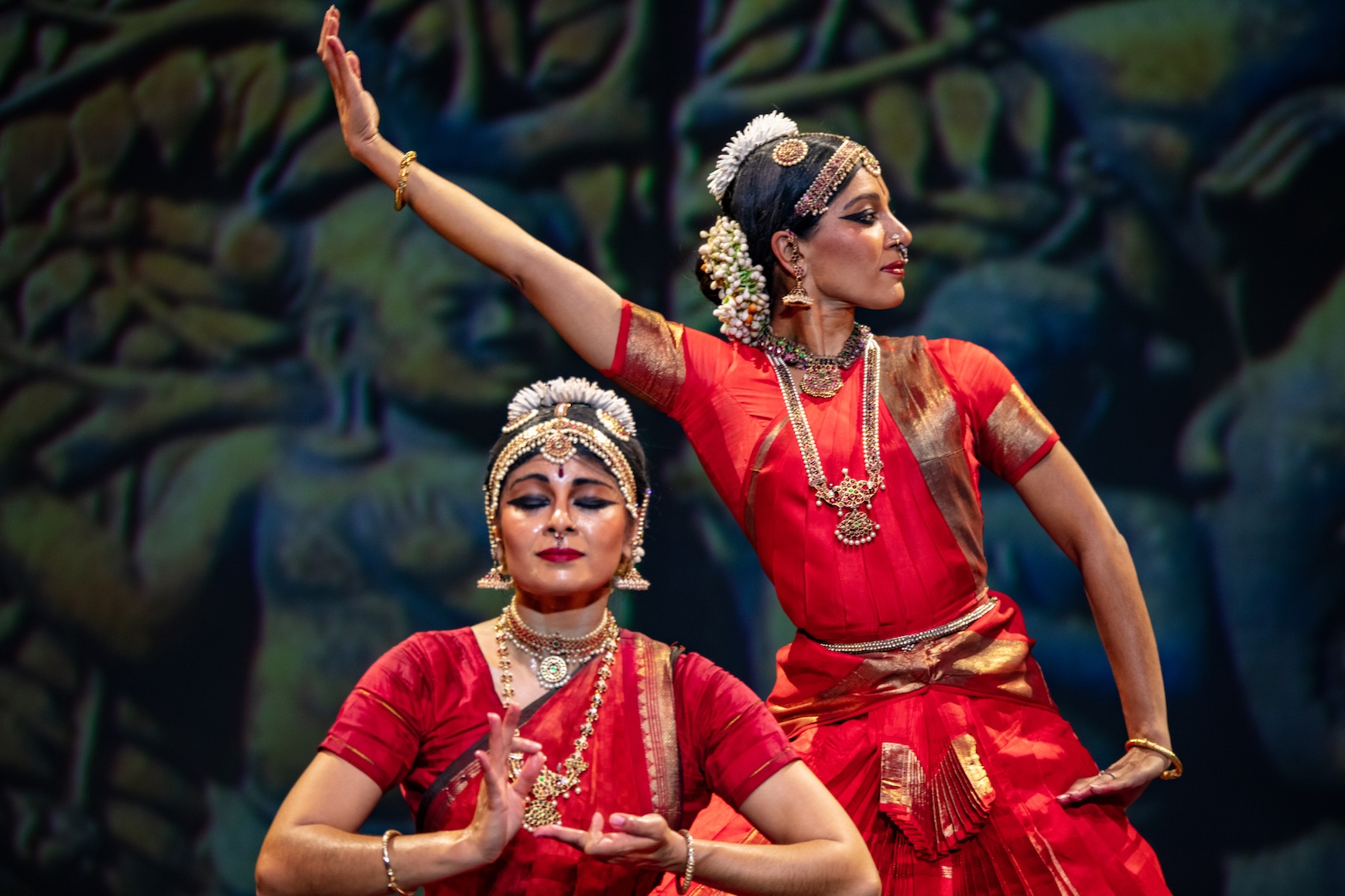 photo of two women in a dance pose wearing red and gold south Indian dance costumes