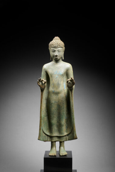 Statue of Buddha standing upright, with both hands making an "O" by touching index finger to thumb