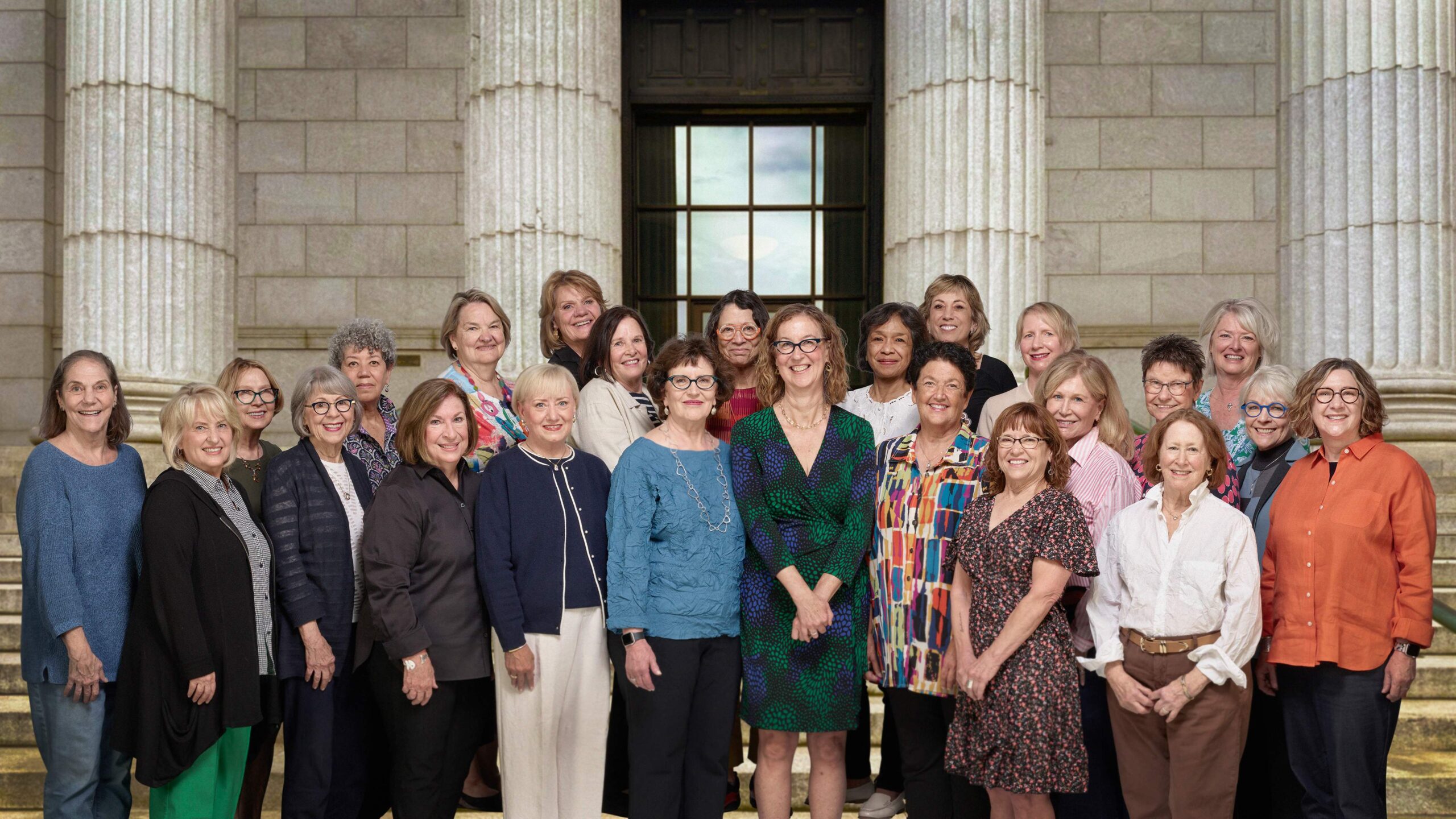 A large group photo of people standing on steps in front of the columns at Mia's entrance