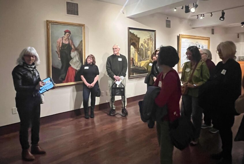 Photo of older adults standing in a gallery listening to someone give a tour