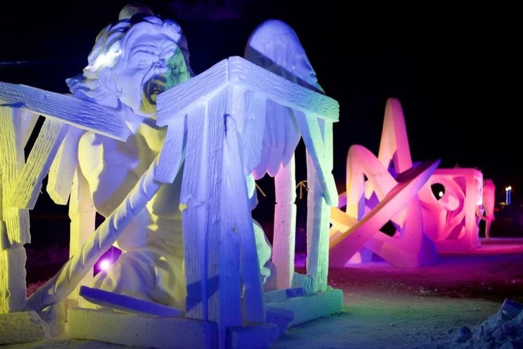 Photo of several large ice sculptures illuminated with colorful lights during the night.