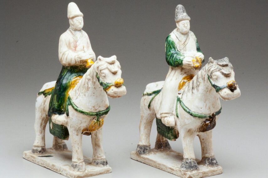 Two ceramic figures on horses with green and yellow details.