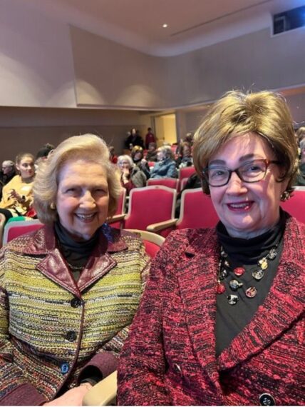 Photo of two older women sitting next to each other in an auditorium