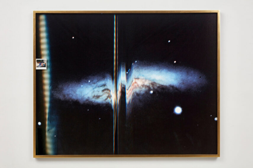 Framed image of a galaxy with a small photo attached.
