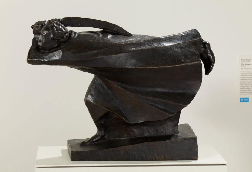 Bronze sculpture of a person bending forward holding a long sword over their shoulder.