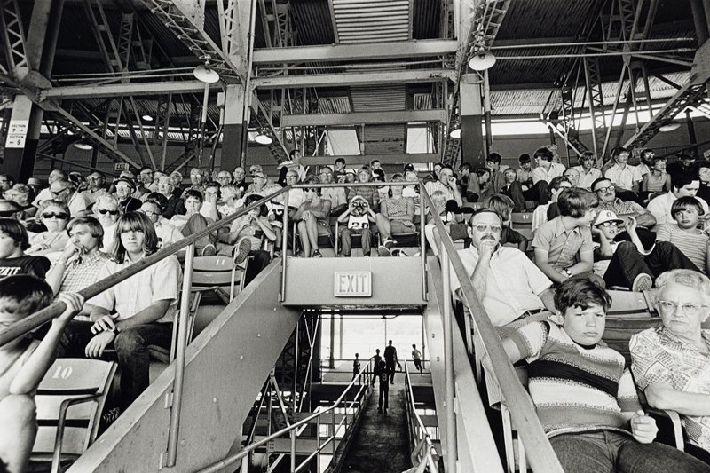 Black-and-white photograph of people sitting in the stands of a stadium