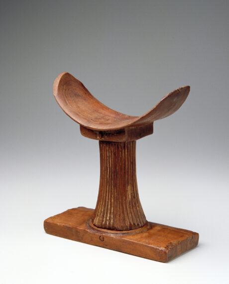 Wooden sculpture with a curved seat on a ribbed column.