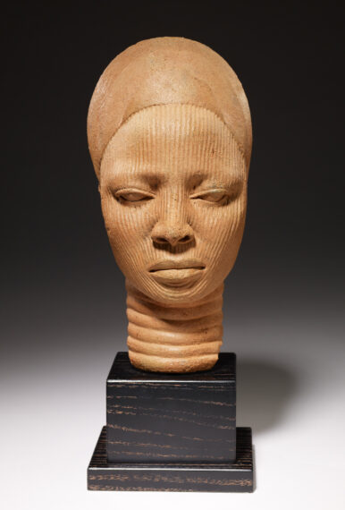 Textured terracotta head sculpture on a dark wooden base.