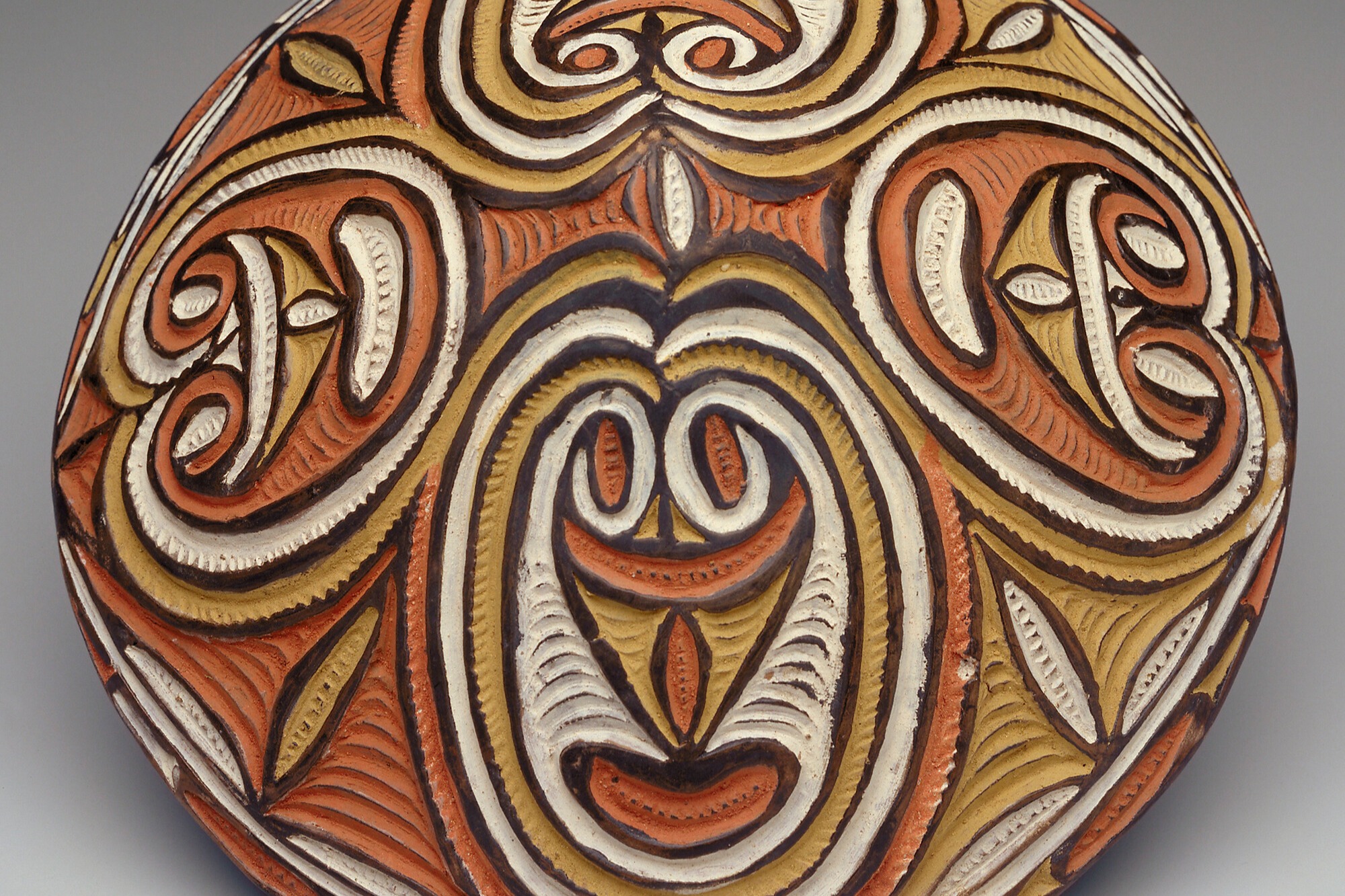 Decorative oval object with intricate red, white, and brown designs.