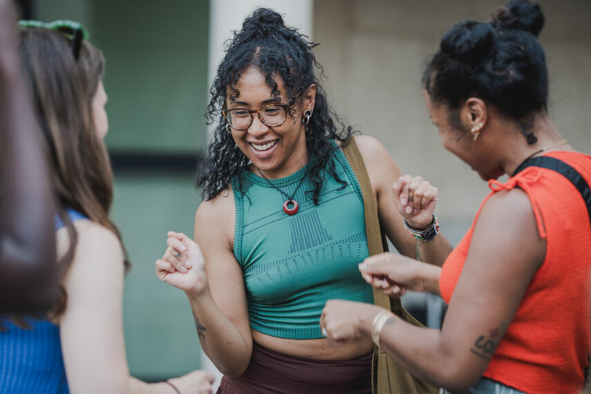 Three women dancing together outdoors.