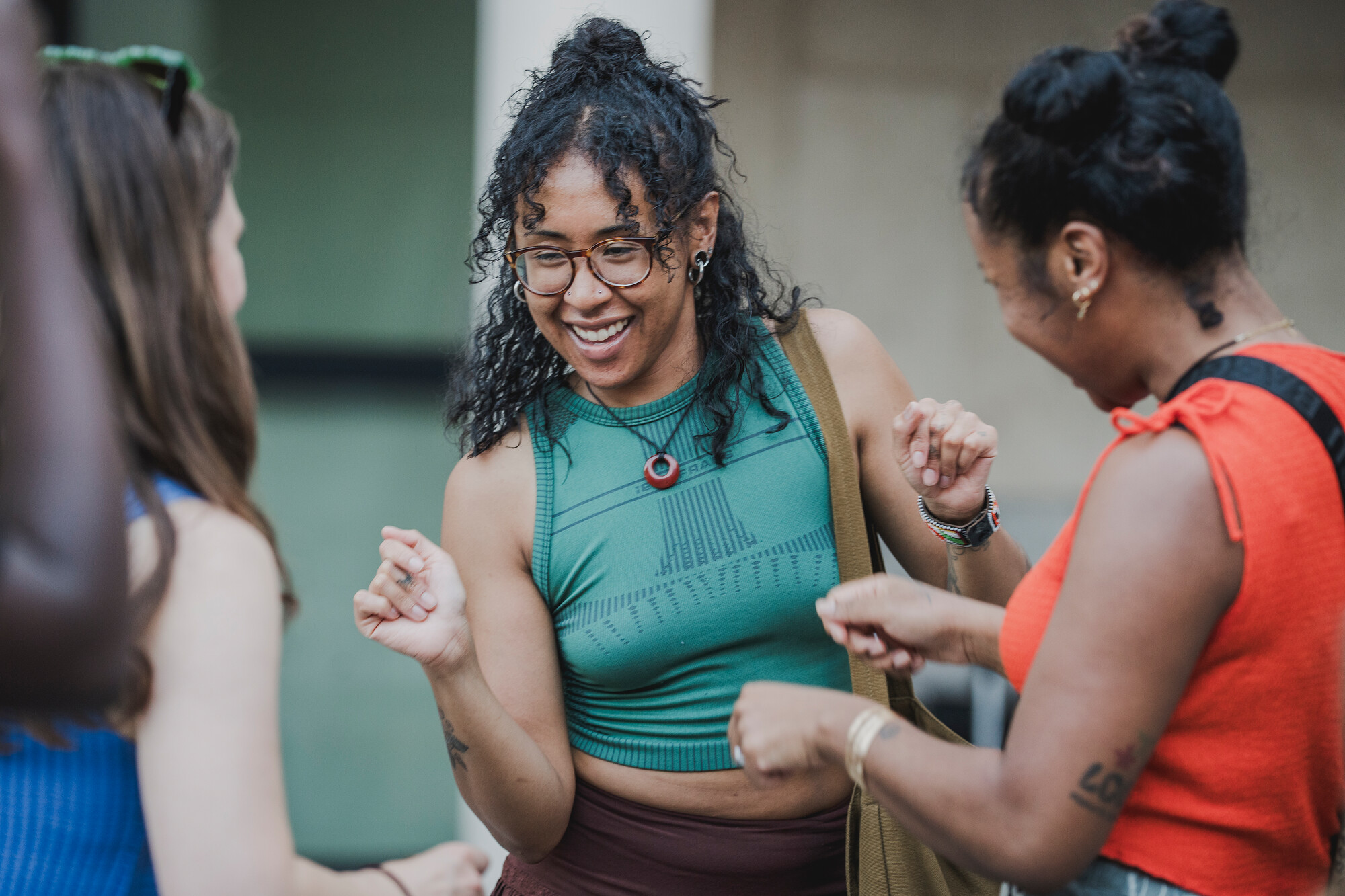 Three women dancing together outdoors.
