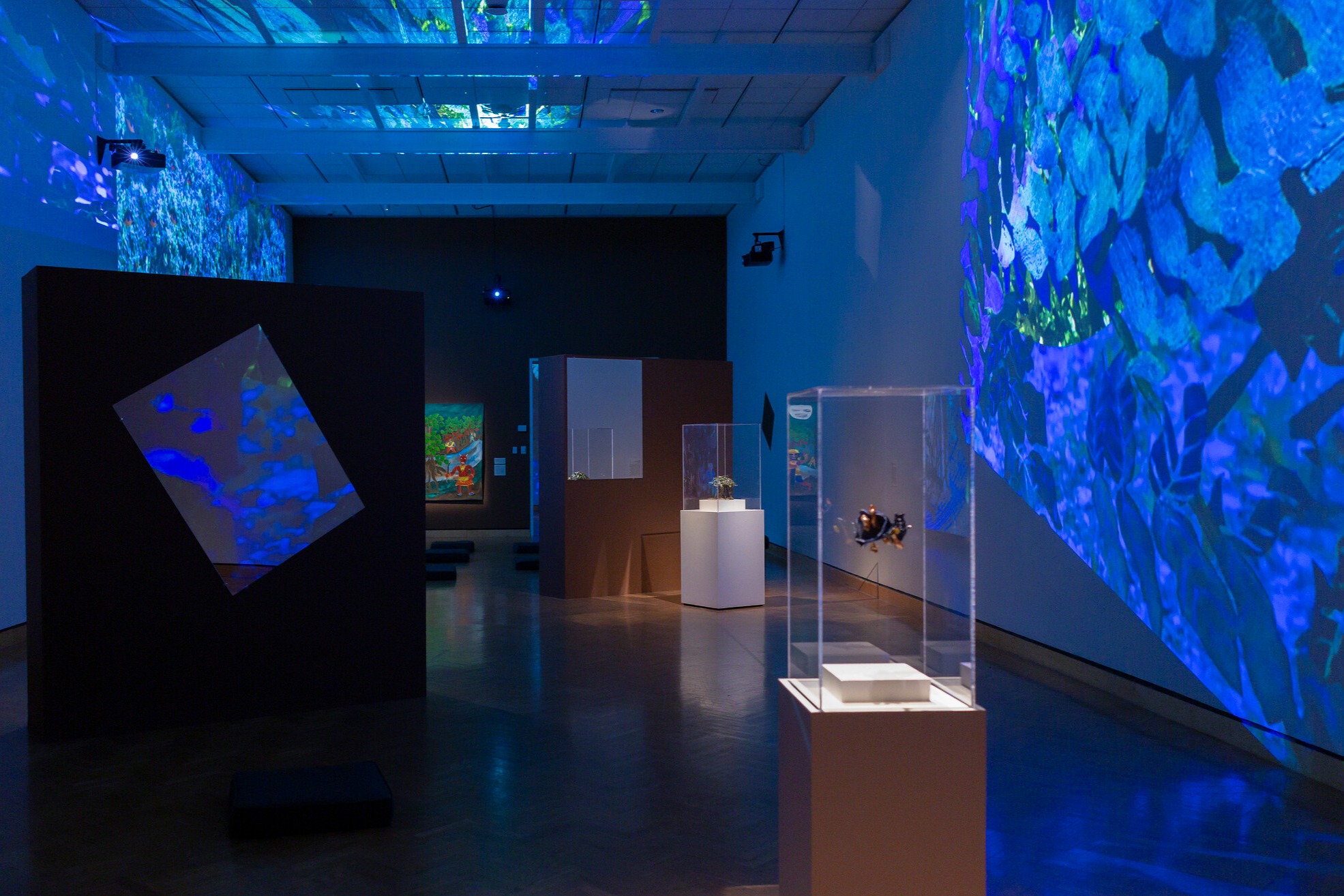 Museum gallery with blue and green light projections on walls.
