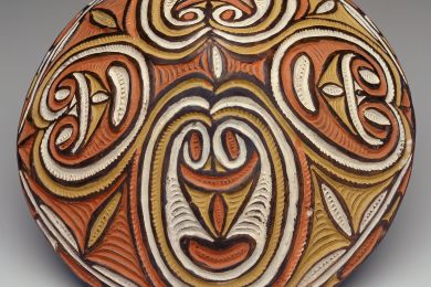 Decorative oval object with intricate red, white, and brown designs.