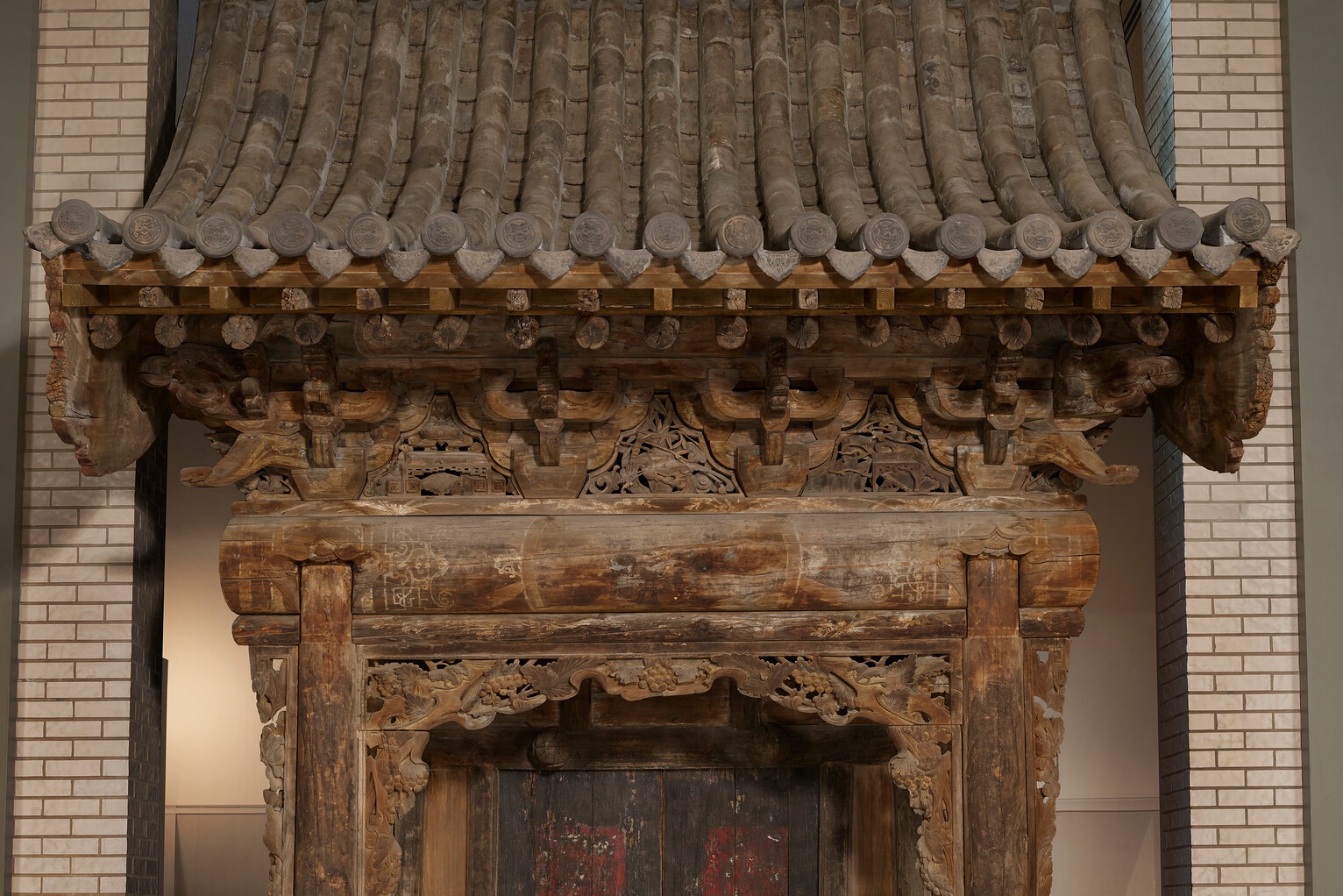 Ornate wooden doorway with carved details and tiled roof.