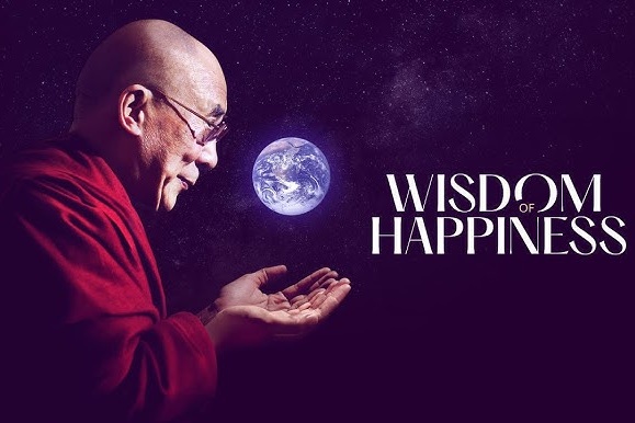 The image shows a man with glasses and a bald head wearing a red robe. He is turned to the left, looking at a glowing image of Earth that floats in front of him. His hands are outstretched as if gently supporting or presenting the Earth. The background is dark with a starry appearance, resembling space. To the right of the Earth, the text reads 'Wisdom of Happiness' in large, white letters.