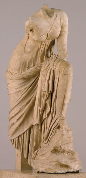 Fragment of an ancient marble statue wearing a draped robed with a missing head and arms.