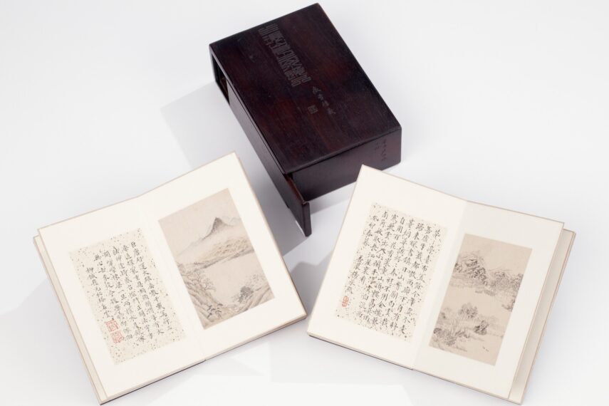 Two open books with Chinese calligraphy and drawings next to a wooden box.