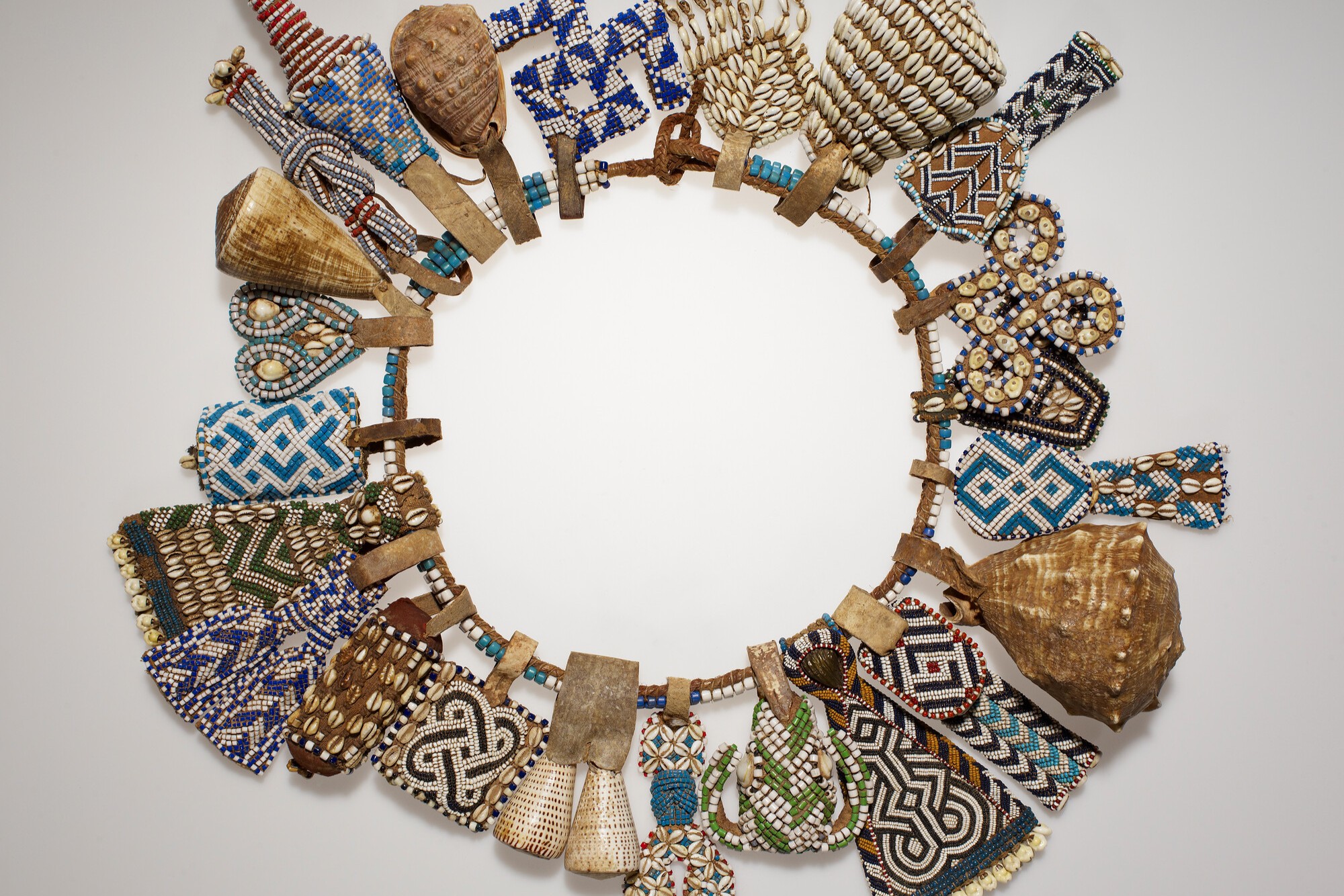 The image shows a large circular necklace decorated with a variety of colorful beads, shells, and patterns.