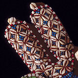 The image shows a close-up of an artistic pattern featuring small cowrie shells and colorful beads.
