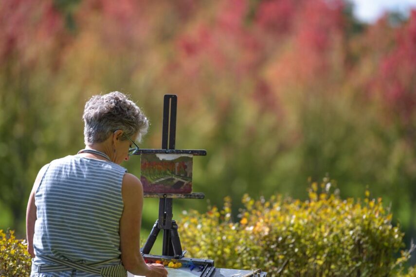 Person painting outdoors with trees in the background.