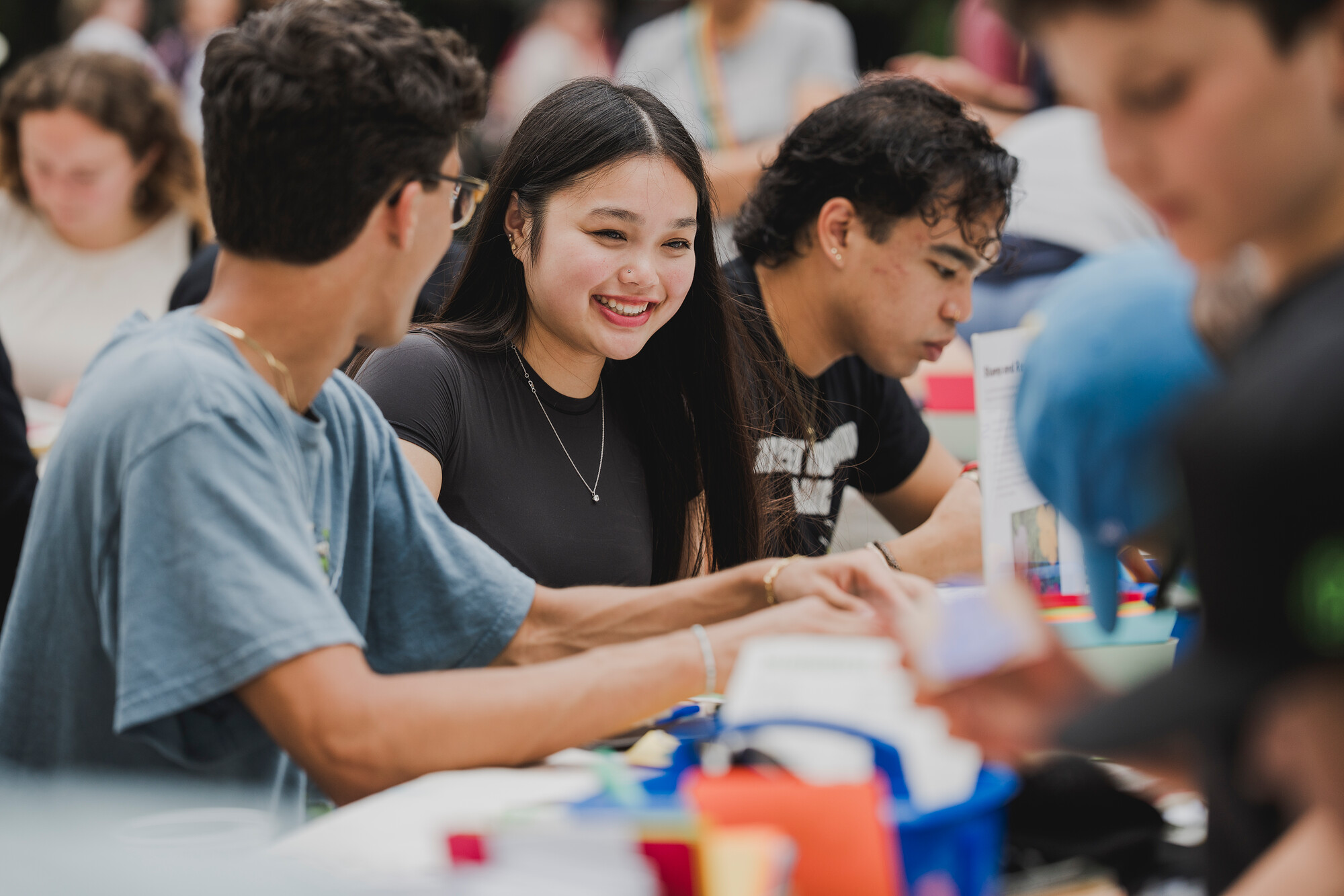 Group of young people sitting at a table outdoors.