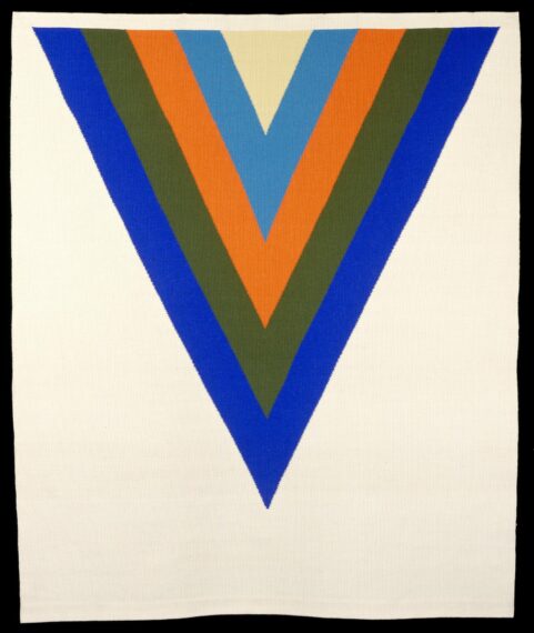 The image shows a textile with a large V-shaped pattern that points downwards. The pattern consists of five concentric V shapes in different colors: blue on the outside, followed by olive green, orange, sky blue, and beige in the center. The background of the textile is white.