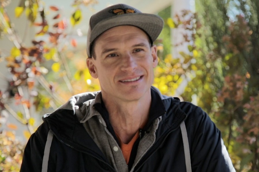 Photo of a person wearing a jacket and baseball hat outdoors