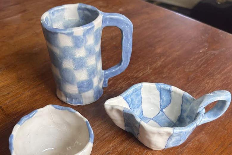 Three handmade ceramic items with a blue and white checkered pattern sitting on a wooden surface