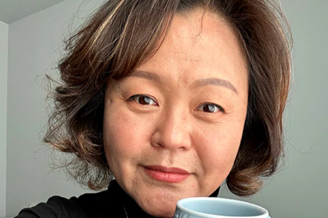 Photo of a woman with chin-length brown hair wearing a black turtleneck holding a light blue coffee mug