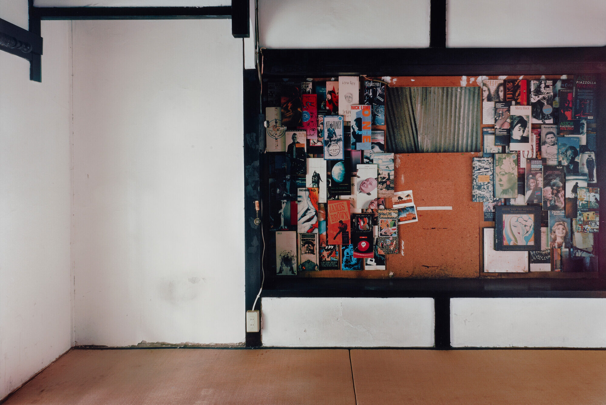 The image shows a room with a bulletin board densely covered with a variety of images, photos, and magazine pages.