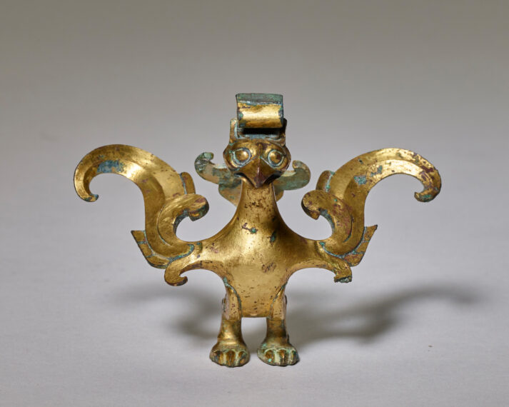 Gold-toned bird sculpture with large, curved wings.