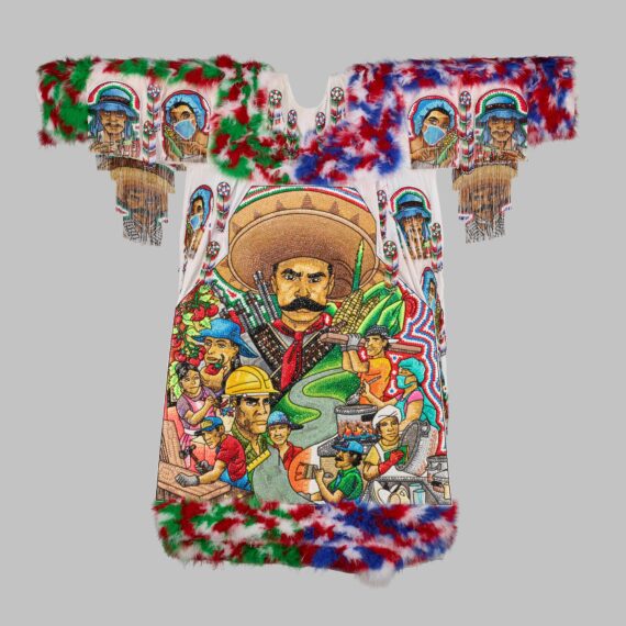 The picture shows an elaborately decorated garment, featuring intricate beadwork depicting a central portrait of a man with a large sombrero and mustache. Surrounding him are smaller portraits of different people, including workers with helmets, a woman with a headscarf, and various individuals engaged in activities like cooking and harvesting. The top and bottom edges are adorned with feathers in green, red, white, and blue.