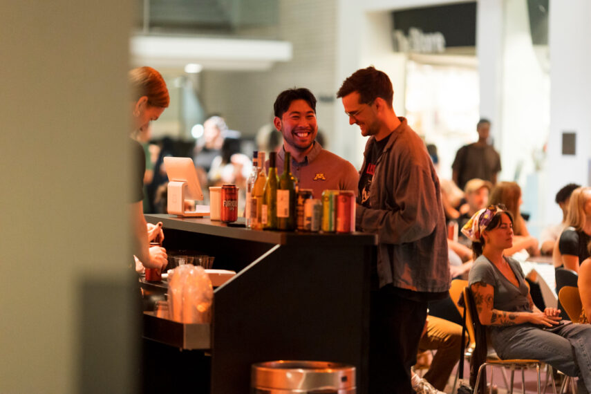 People socializing at a bar with drinks on the counter.