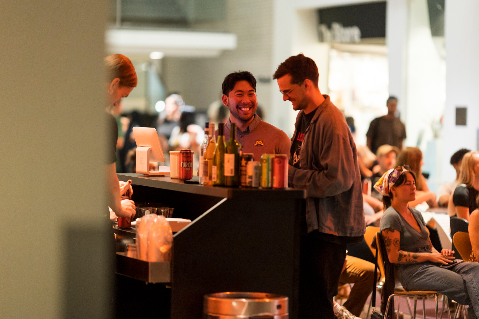 People socializing at a bar with drinks on the counter.